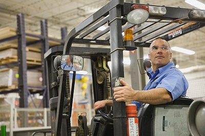 Worker driving forklift in factory